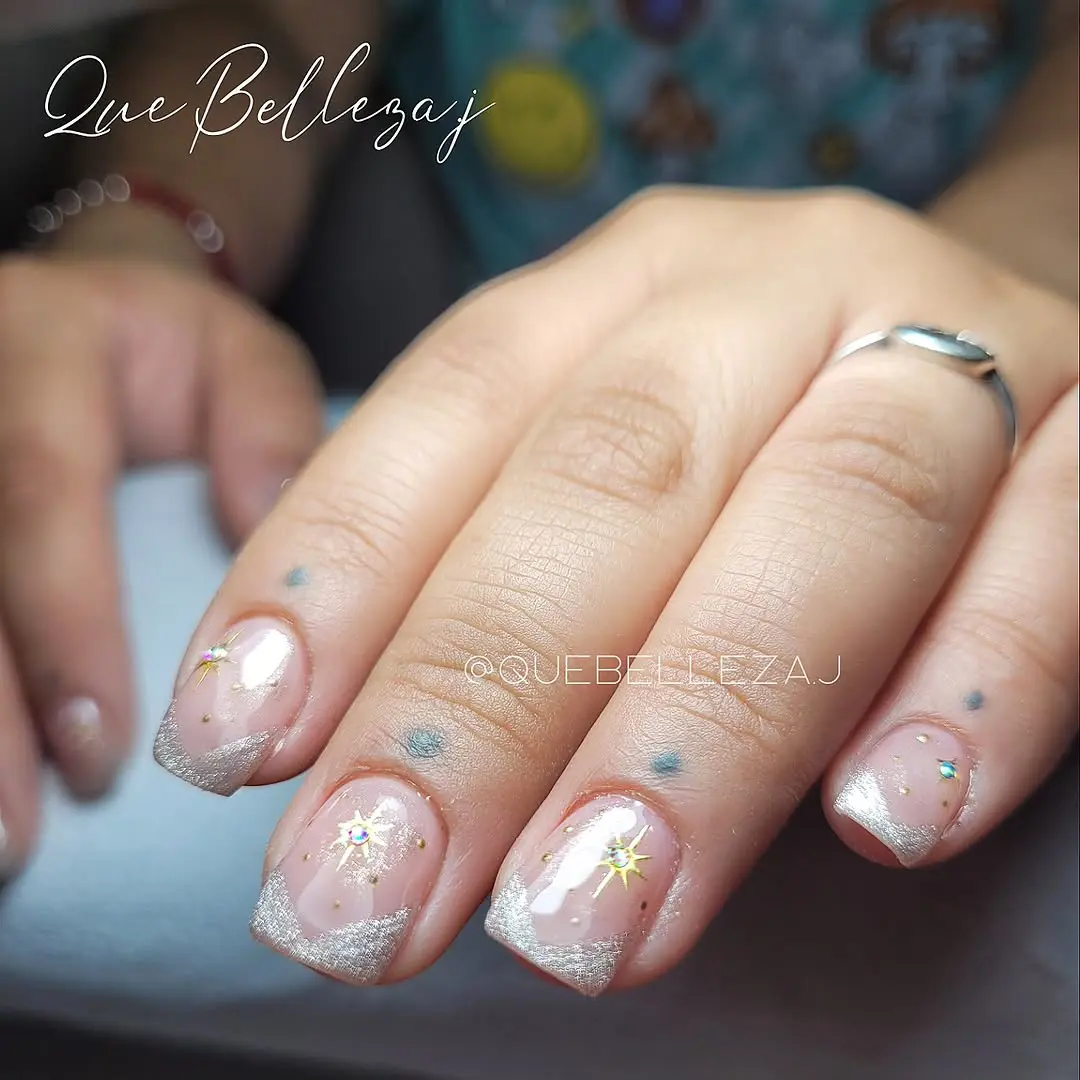 Uñas nude con puntas plateadas y estrellas doradas